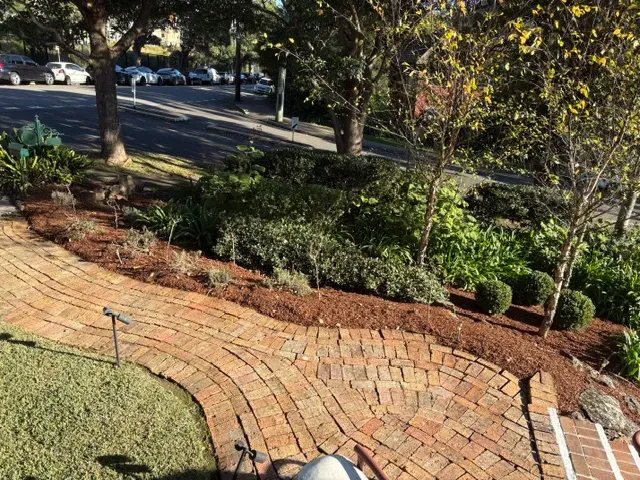 Freshly mulched garden bed beside a curved brick path